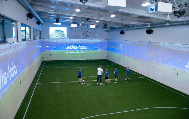 Blog - Innenaufnahme der KIB Sport One Arena während der Eröffnungsfeier mit einem Trainer und mehreren Nachwuchsspielern